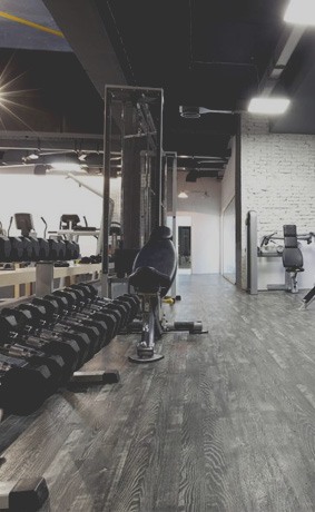 Hip Thrust Machine vs Barbell: Which Is Better? 4 Gym floor with dumbbell rack and strength machines