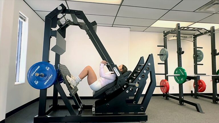 Woman training glutes and quads on the GluteZone Pendulum Squat machine in a commercial gym