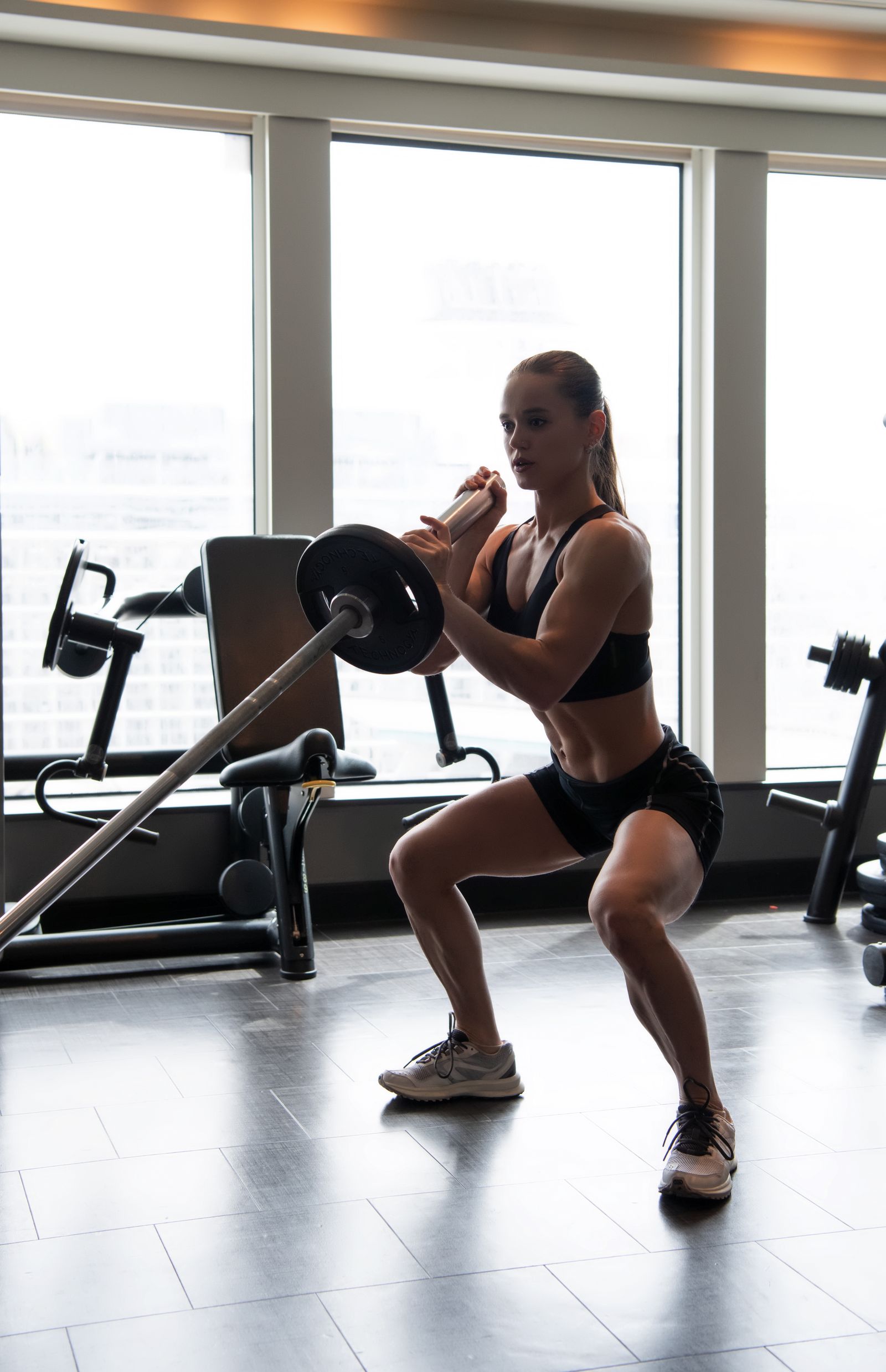 The Loaded Stretch: Why Deep Hip Extension Builds Bigger Glutes 3 Female athlete performing a deep barbell squat in a commercial gym
